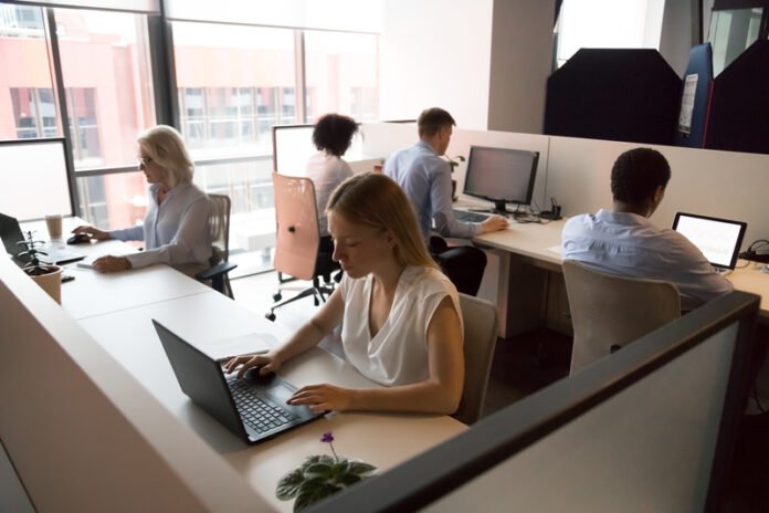 Employees working in coworking office sitting at desk using computers